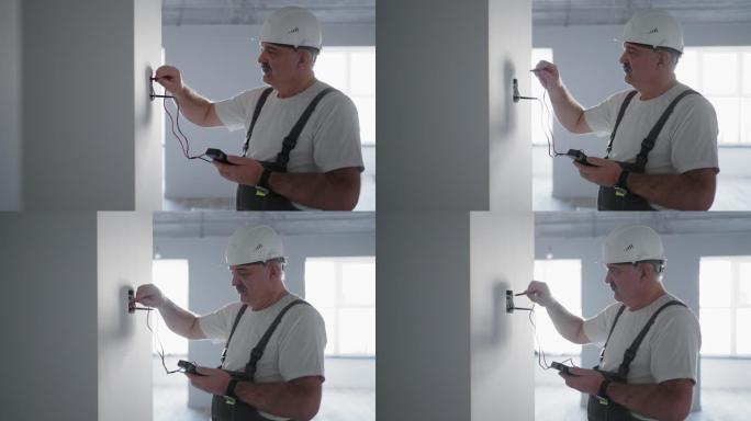 一名男电工用准备安装智能家居的电线测试仪检查网络中的电压。由专业电工检查所有系统