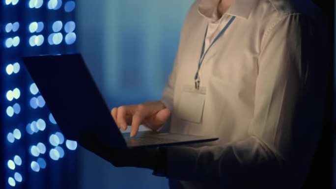 用笔记本电脑在服务器机房工作的人的脸像。技术员在服务器机房做检查。穿着灰色工人夹克的高加索工程师