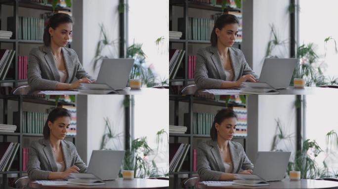 西班牙裔女性在笔记本电脑上打字的肖像，向客户发送电子邮件，并对结果感到满意。坐在桌旁的女商人