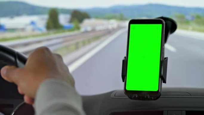 男子在高速公路上开车，看着智能手机上的导航
