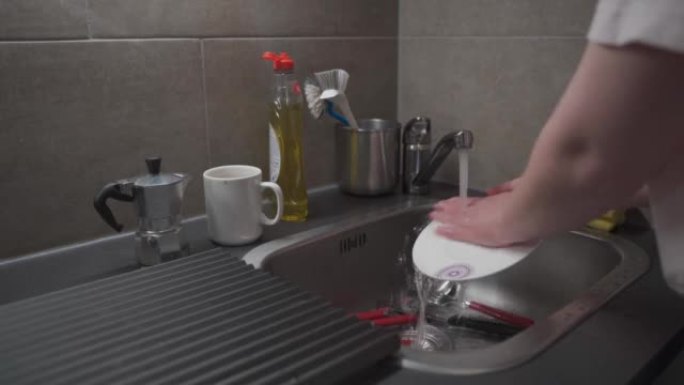 特写女性在厨房的家中洗手厨房水槽用具，并使用清洁液。主题是家务和家务。打扫房子，家常便饭。家务