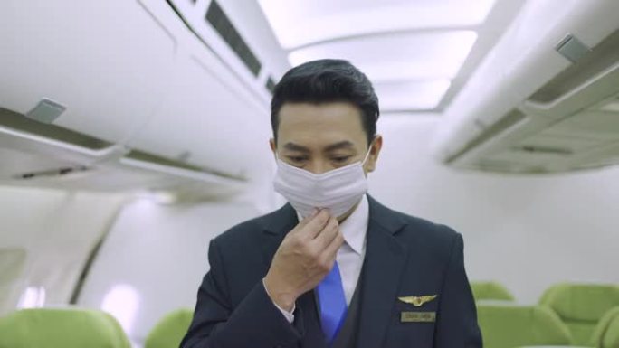 亚洲男空姐戴着医用口罩站在飞机上