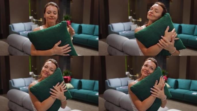 微笑女人拥抱绿色靠垫的肖像站在家具沙龙思考。快乐自信的高加索女性客户在室内商店的黑色星期五销售中选择