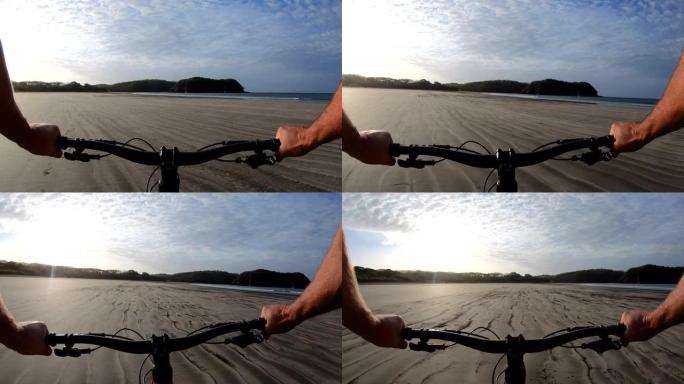 男子在日出时沿着空旷的海滩骑自行车