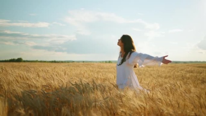 受启发的年轻女子在夏天独自走在金色的黑麦田上，欣赏农业景观
