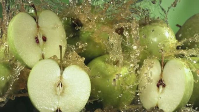 绿色苹果汁溅过苹果片的慢动作镜头