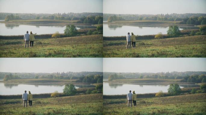 慈爱的老年夫妇站在湖边。欣赏风景
