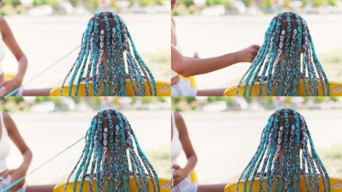一个穿着西装的女孩在阳光明媚的日子里在头发上编织非洲辫子