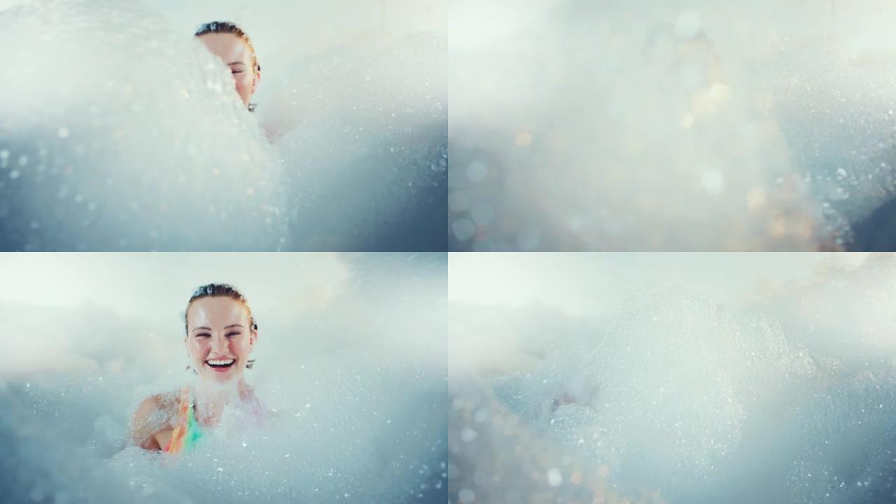 美丽的女人享受着泡沫泡泡浴，对着镜头微笑。特写镜头。慢动作