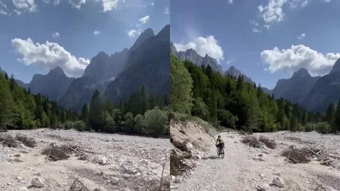 骑自行车的人沿着山区的岩石河岸骑行
