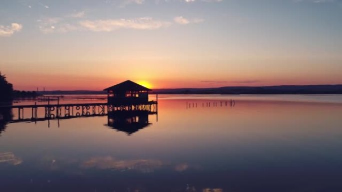 在美丽的日落时分，缓慢而平稳地在湖上钓鱼码头和海水中的旧平房上移动