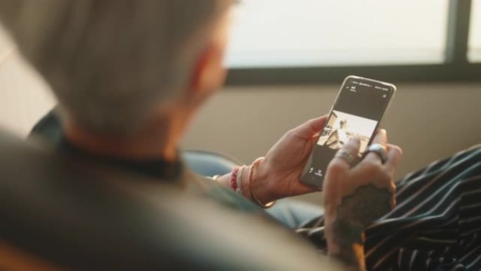 一位老年摄影师用智能手机通过窗户拍照。