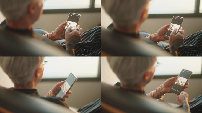 一位老年摄影师用智能手机通过窗户拍照。