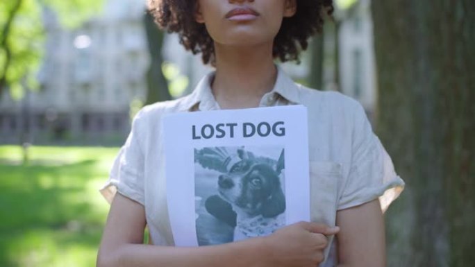 女狗主人手拿失踪宠物海报，寻找丢失的宠物