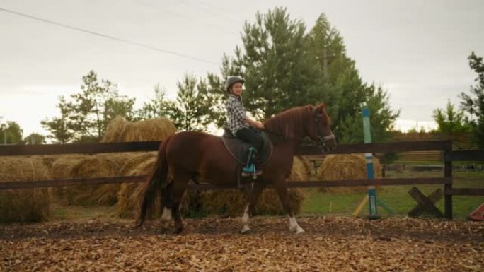 夏天，小骑师女孩在牧场的围场骑小马，马术课