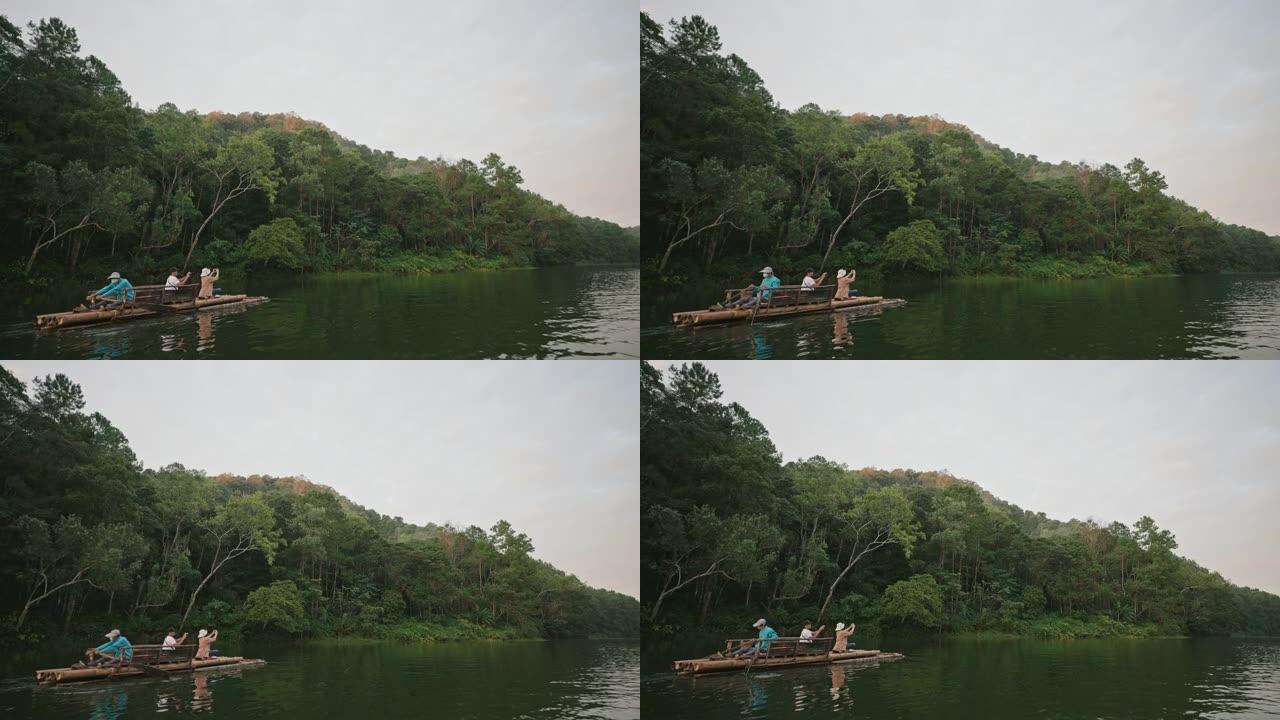 一位游客坐在竹船上拍照，欣赏森林和度假时的湖泊自然。