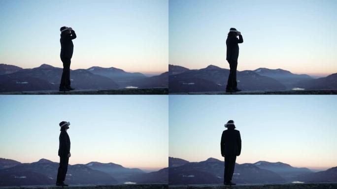 男子戴着VR虚拟现实护目镜在户外的山中俯瞰夕阳的湖泊，环顾四周