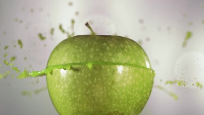 半个青苹果掉落并溅到白色背景上。食物悬浮概念。慢动作