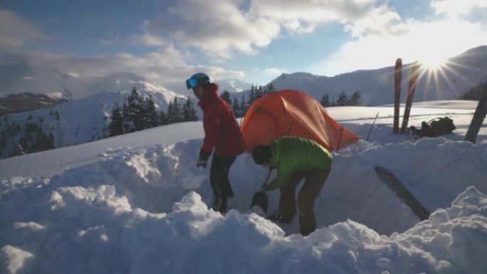 一对滑雪者在雪山上架起帐篷