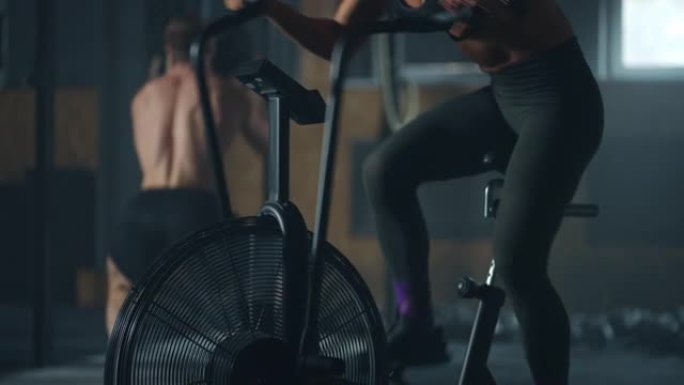 在带风扇的固定自行车上进行有氧训练，女人用力旋转踏板，锻炼身体健康