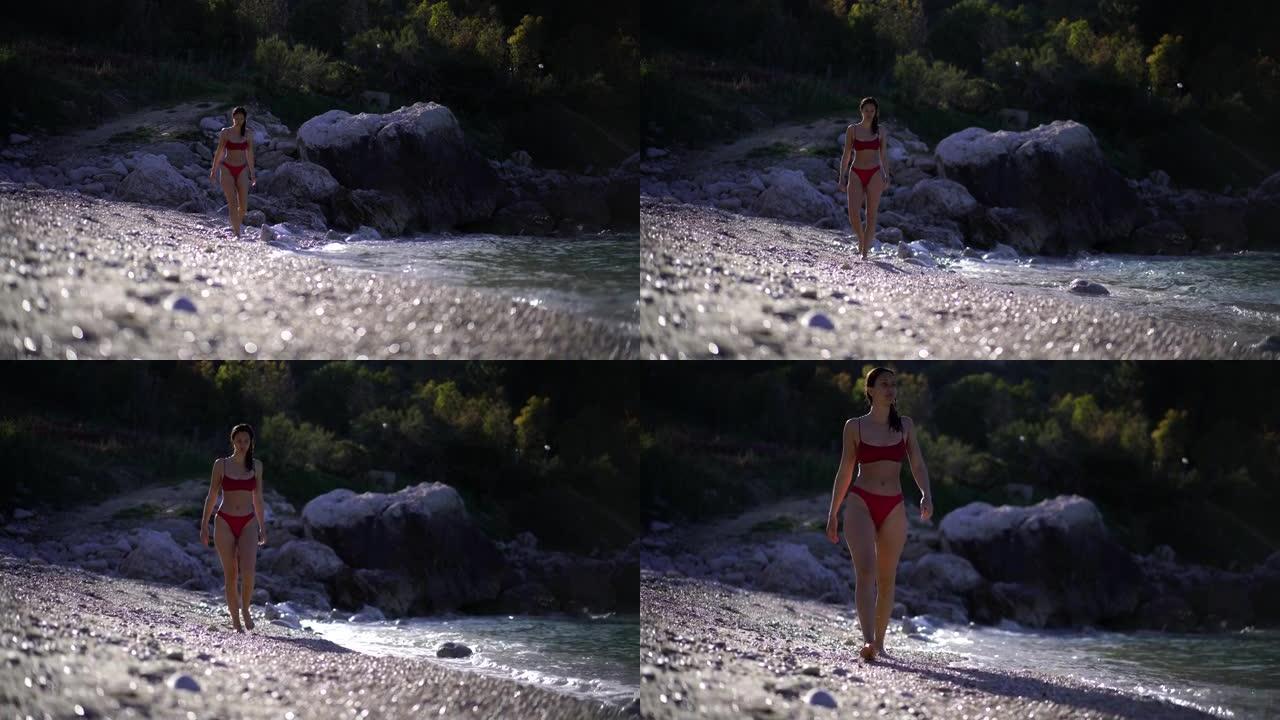 穿着泳装的年轻女子在海滩上走向相机