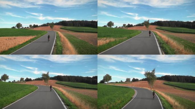 女自行车手在乡村丘陵公路上坡骑行穿过田野和草地。女铁人三项运动员骑自行车，爬上去，做有氧运动。耐力自