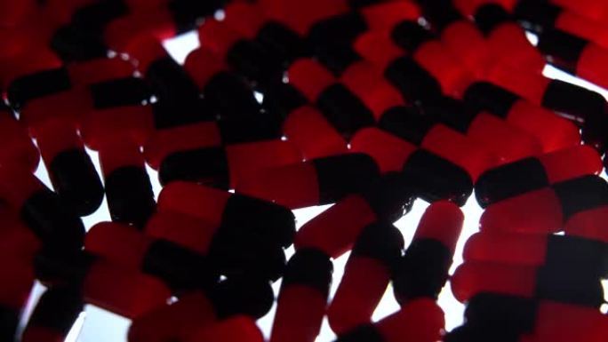 红色和黑色胶囊药丸旋转与黑色照明