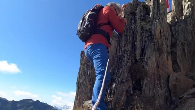 男性登山者攀登陡峭的岩石山脊