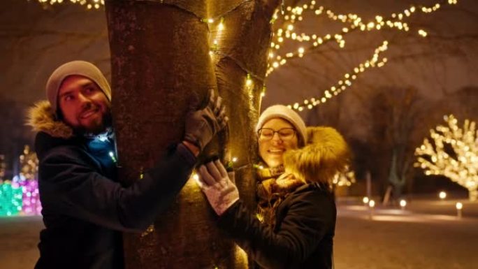 在一个下雪的夜晚，一对夫妇在慢动作中拥抱圣诞树。牵手