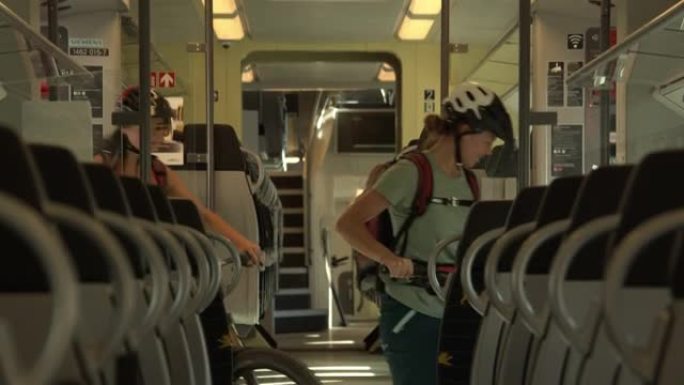三名年轻妇女将山地自行车骑上火车