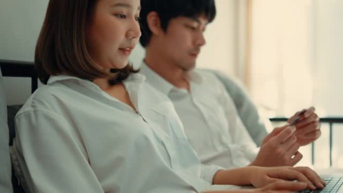 年轻夫妇在沙发上休息时，喜欢一起在笔记本电脑上购物。