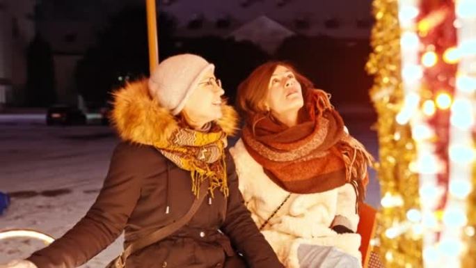 两个女性朋友在下雪的圣诞节夜晚一起慢动作旋转木马