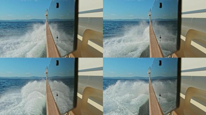 游艇的SLO MO LD侧面在海上快速行驶，海浪在玻璃上反射