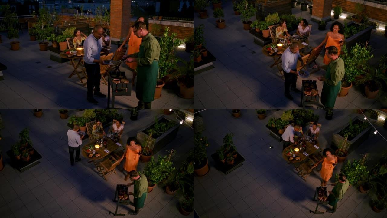 CS男子晚上在屋顶的烧烤派对上将烧烤食物放在朋友盘子上