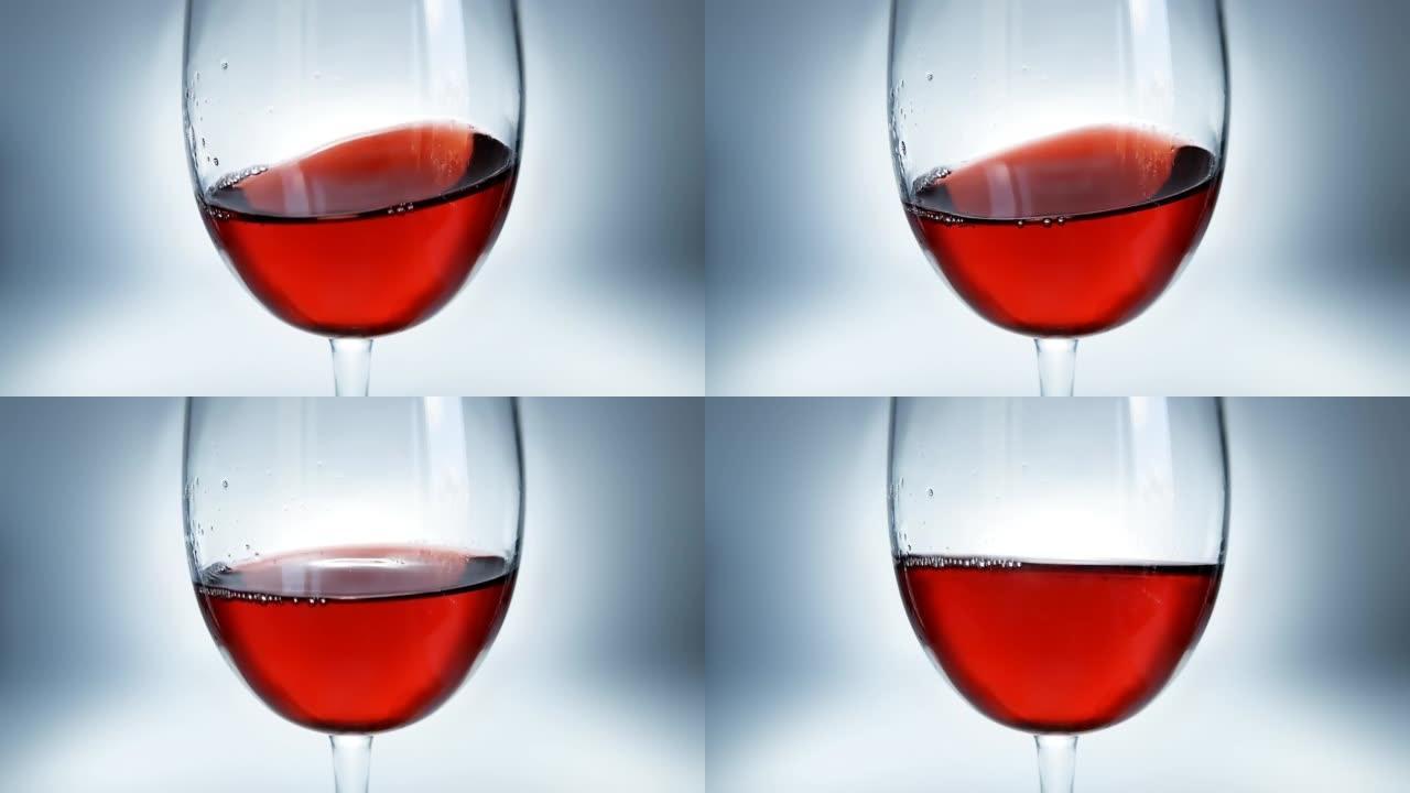 红酒溅在杯子里。在玻璃杯中挥舞酒特写。4k微距慢动作视频。在高速电影摄像机上拍摄。