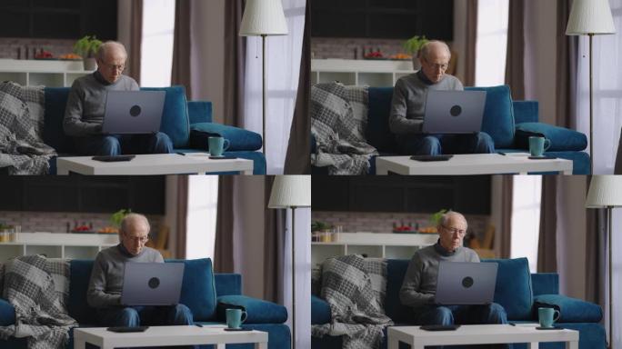 孤独的老人坐在家里，用笔记本电脑工作，退休人员的肖像在他公寓的客厅里