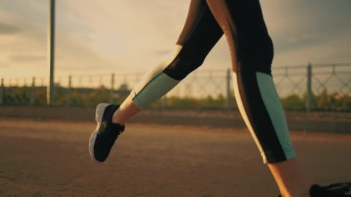 运动女子在日落或傍晚在外面奔跑，穿着运动服的身体特写