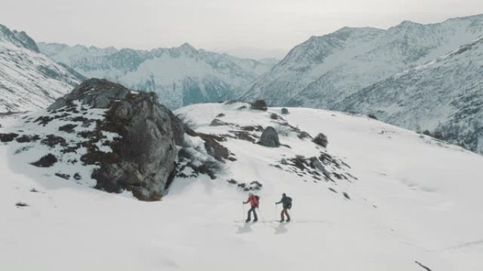 两名滑雪者在雪山上徒步旅行的空中无人机拍摄