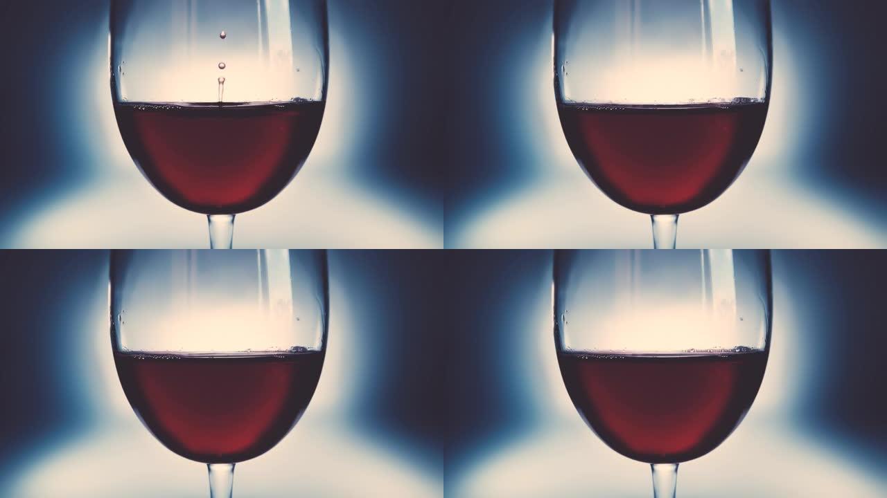 杯子里的红酒和落下的酒滴。酒滴在玻璃杯中慢慢落下特写。4k微距慢动作视频。在高速电影摄像机上拍摄。