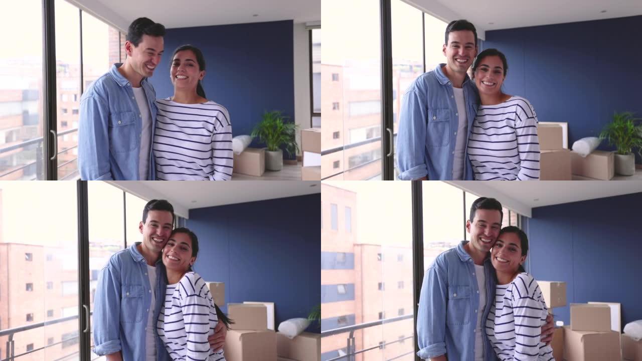 充满爱心的拉丁美洲夫妇互相看着对方，然后面对镜头，在他们的新家中非常开心地微笑
