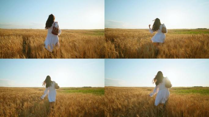 穿着白色连衣裙的迷人黑发女人独自走在美丽的金色黑麦田里，慢动作，后视