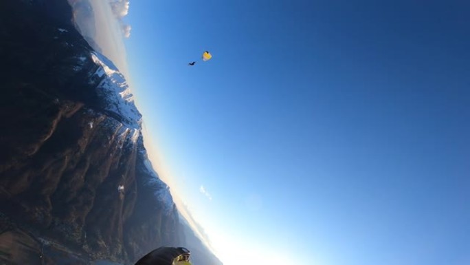 跳伞运动员降落在乡村景观上方的晴朗天空中