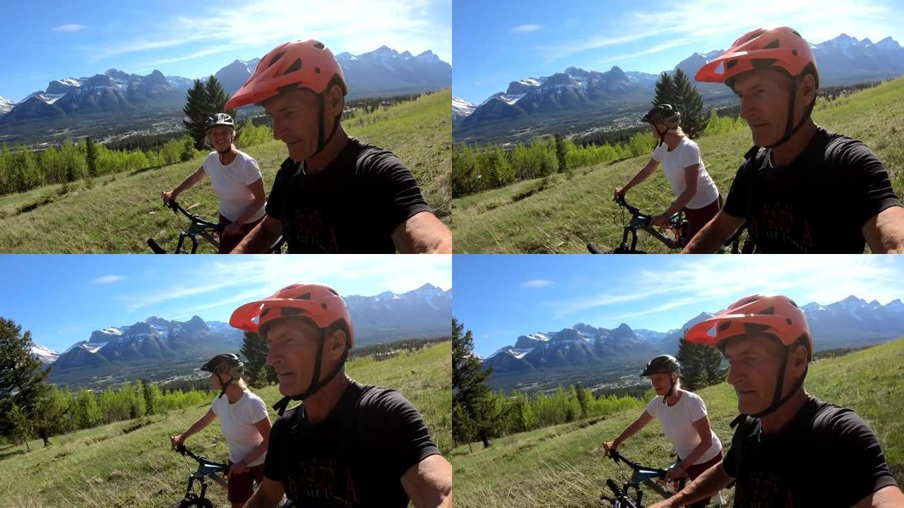 成熟的夫妇将自行车推过山区草地