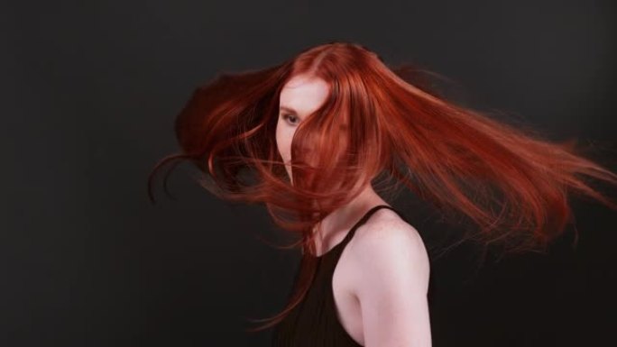 美丽的红发女人，留着健康的长发。转向相机