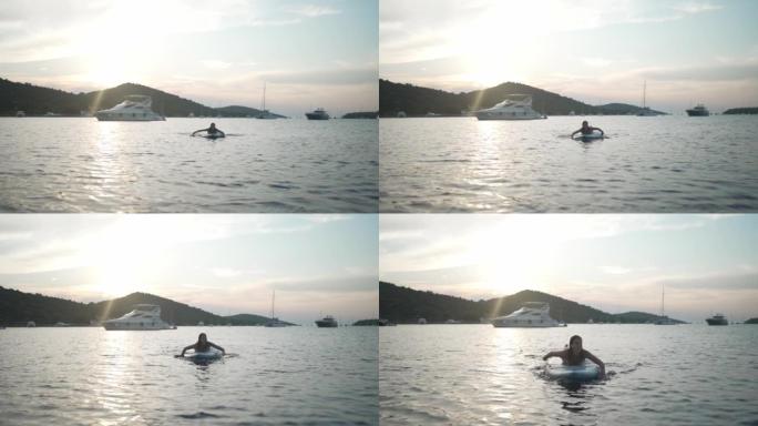 日落时，年轻女子在海湾的木板上划船