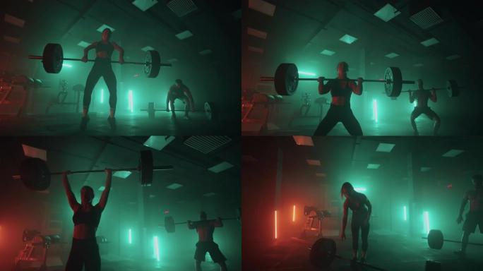 健身馆里的举重训练，两个人在黑暗的大厅里举起杠铃，进行体育锻炼
