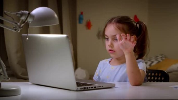 在笔记本电脑上在网上学校学习的小女孩。