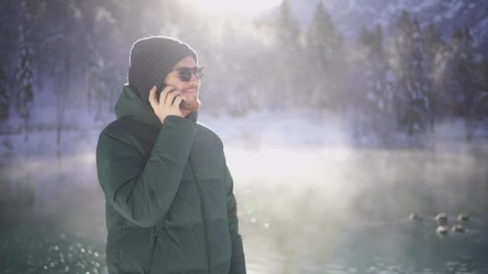 年轻人在白雪皑皑的湖边用手机聊天