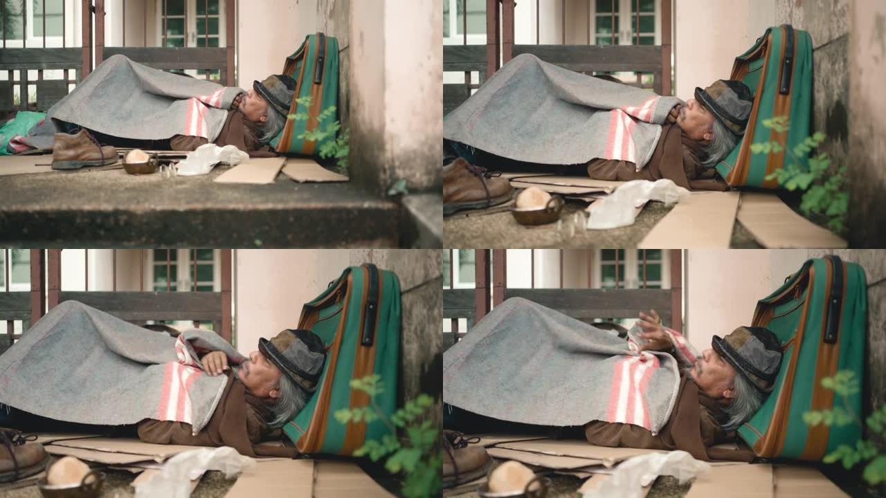亚洲乞丐带着包躺在人行道上，因为在冠状病毒大流行期间失业。