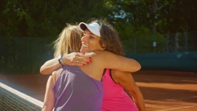 SLO MO两个女人在阳光明媚的日子里在外面打网球后握手拥抱